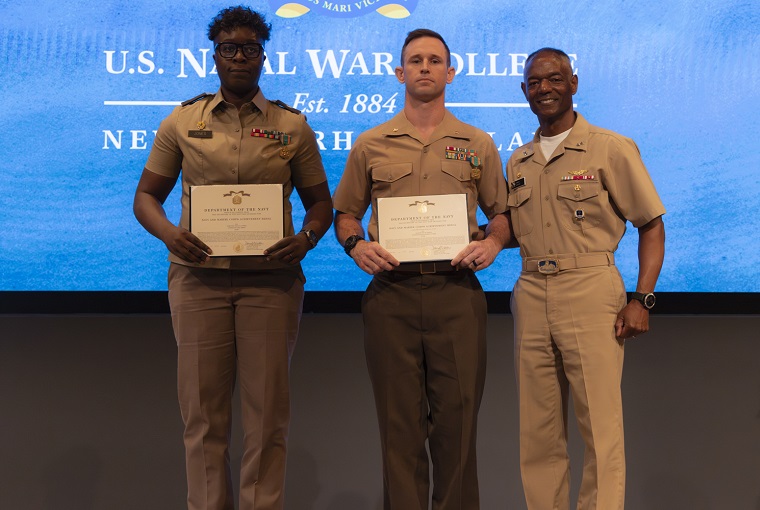 Two students receiving an award from the Naval War College president.